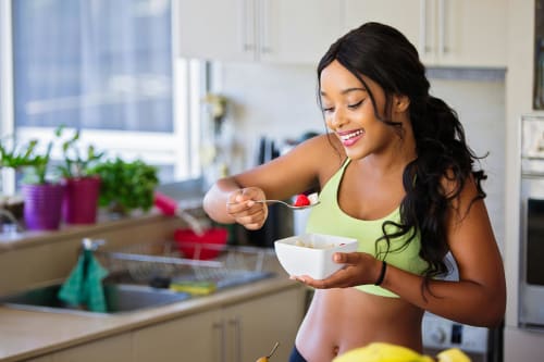 A person gleefully enjoying a plate of fresh fruits and vegetables.