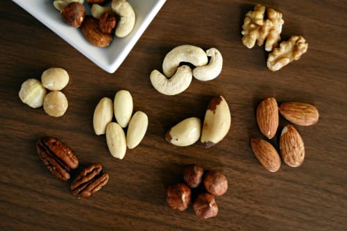 mixed nuts for snack, a photo representing each of the nuts arranged over a wooden board'